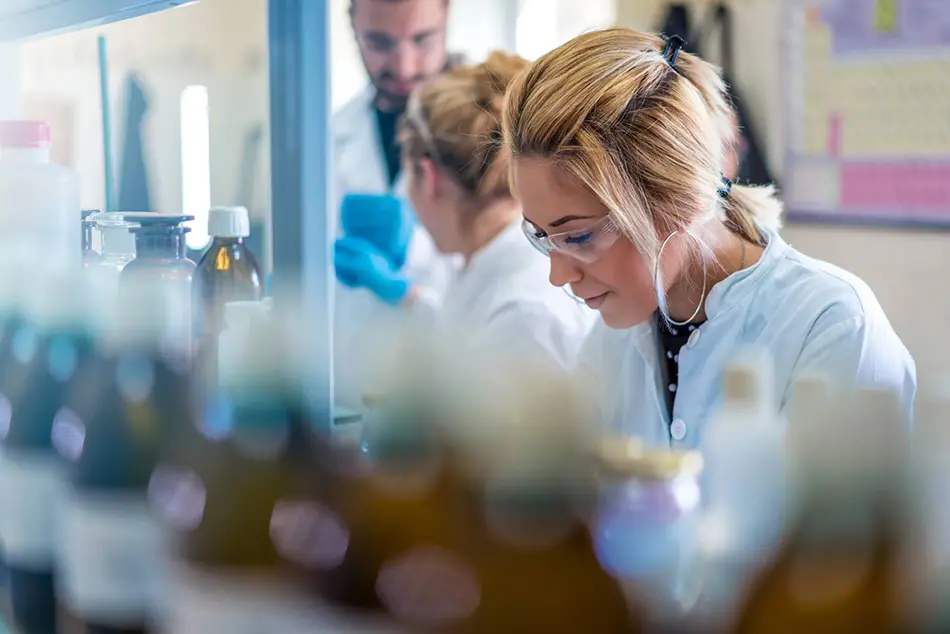 Three researchers in a laboratory, deeply focused on their research endeavors.